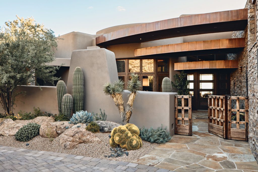 Adobe luxury estate entry — vigas, stone, desert landscape